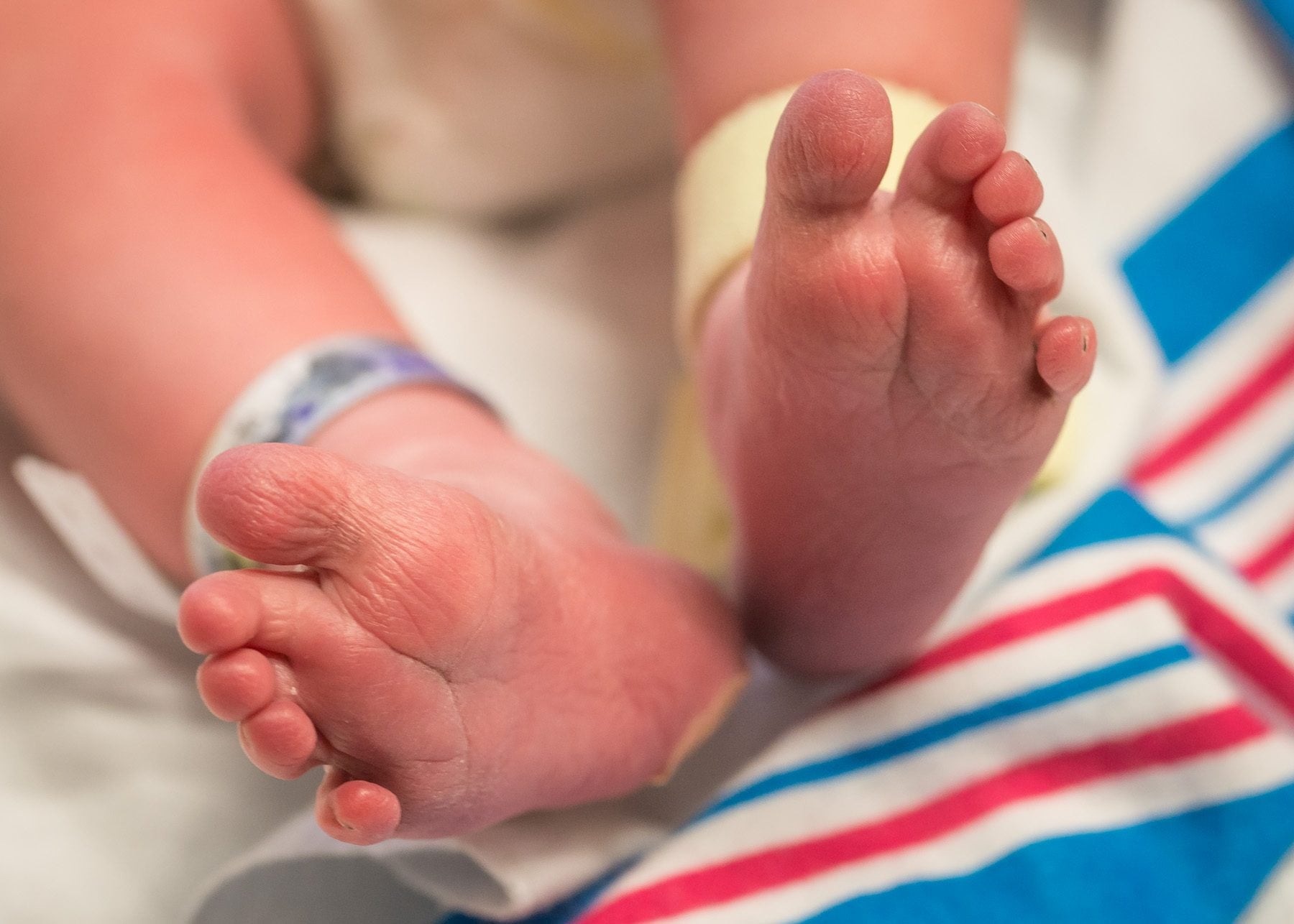 Close-up of a newborn's crossed feet with a hospital identification band on the ankle.